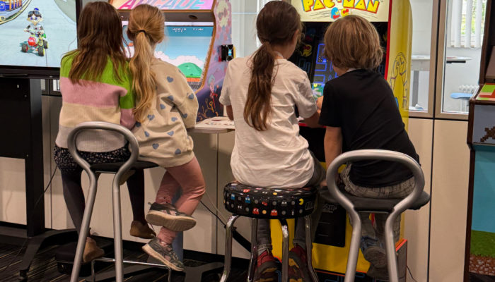 vier Kinder, die an Arcade-Spielstationen sitzen