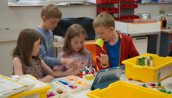 vier Kinder, die mit Legosteinen etwas bauen